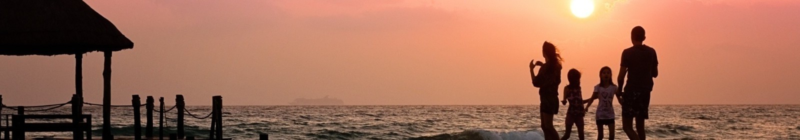 family standing on beach watching sunset