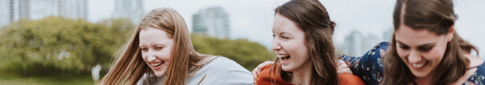 Three girls laughing in front of skyline