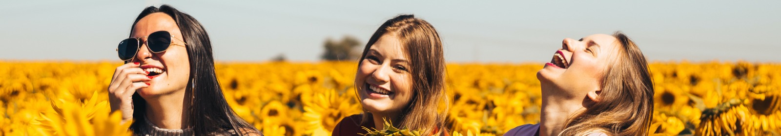 women laughing in field of sunflowers