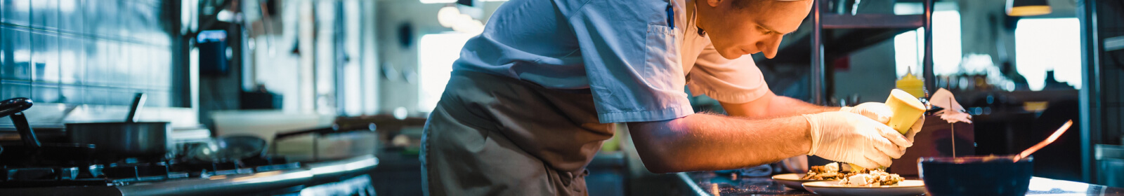 A chef pouring sauce on food