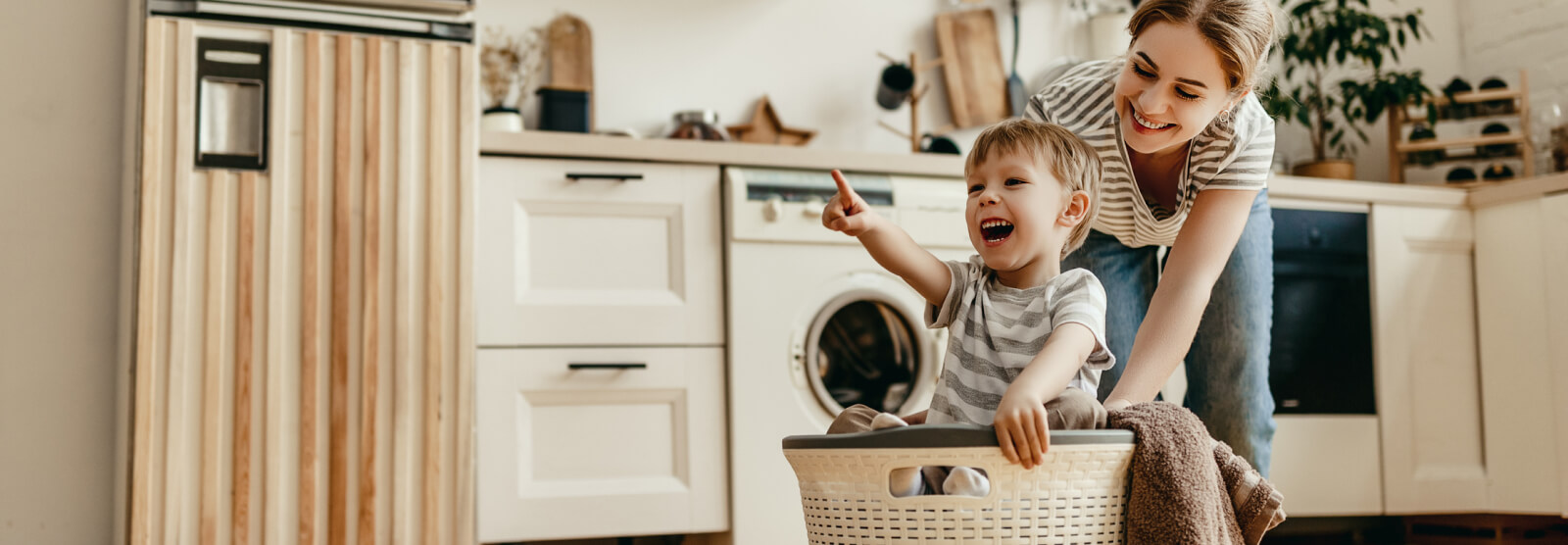 Young mom and toddler playing in a laundry basket